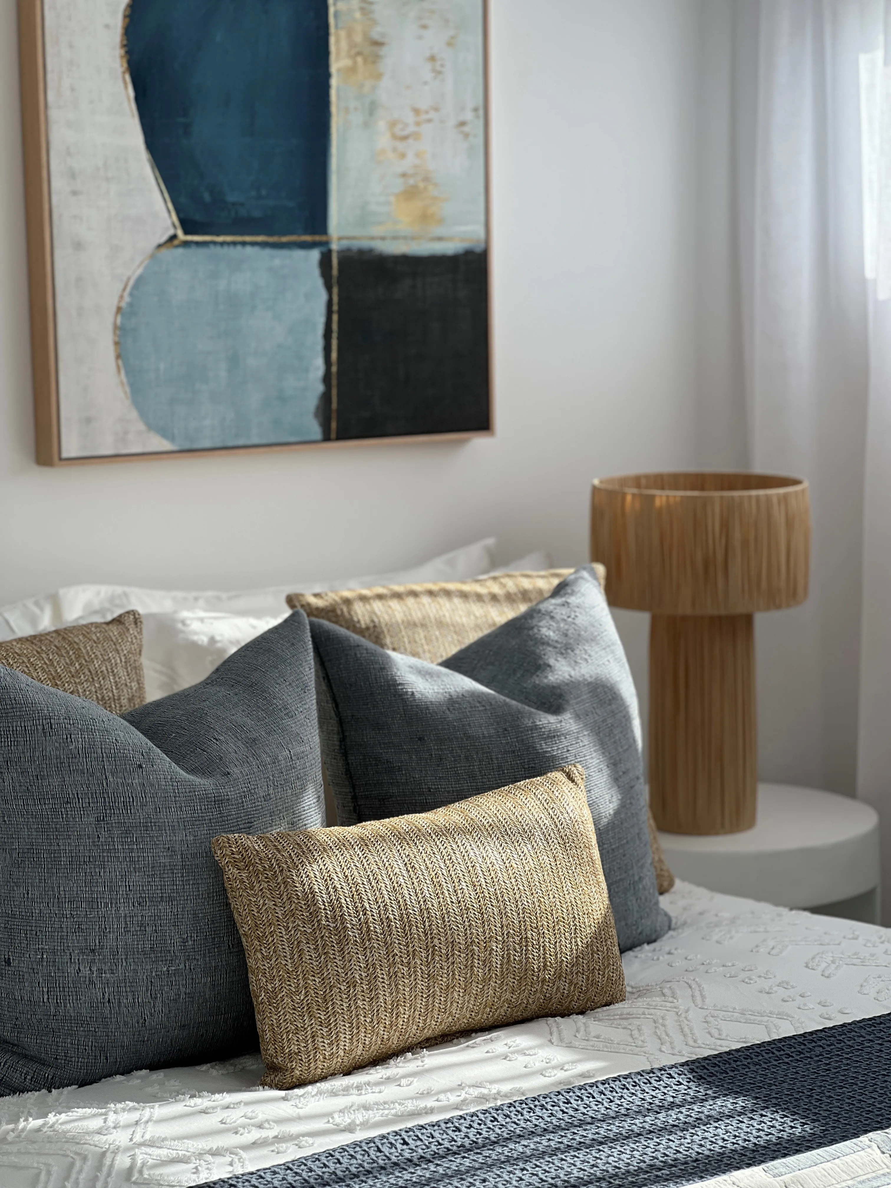 Guest bedroom with blue-grey linen cushions, jute throw and abstract artwork